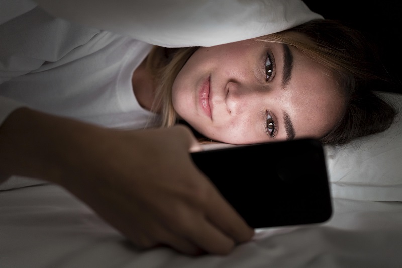 A woman using a cell phone in bed